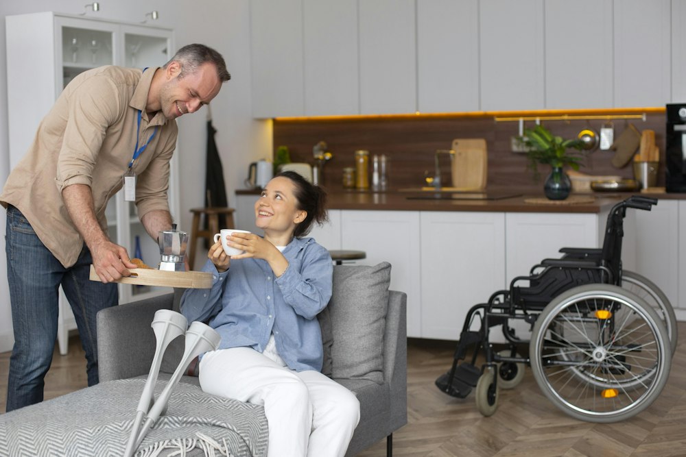 A support worker bringing a meal to a woman at home, her wheelchair beside her